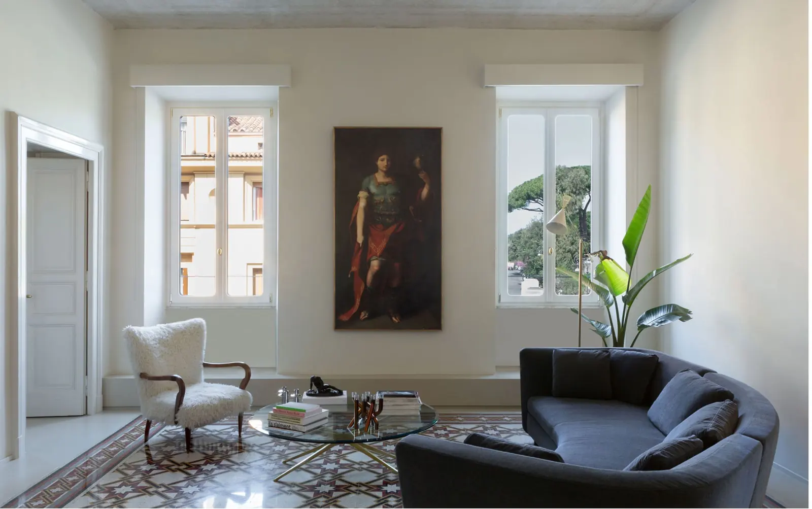 Salone di Casa Mecenate all'Esquilino: pavimento decorato d'epoca, dipinto a parete e divano contemporaneo
