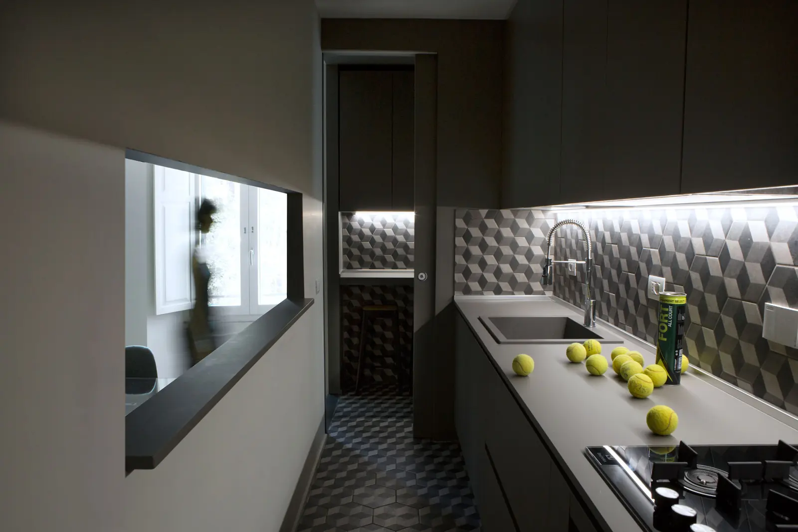 Cucina di Casa Milizie con rivestimento in piastrelle tridimensionali e palette scura