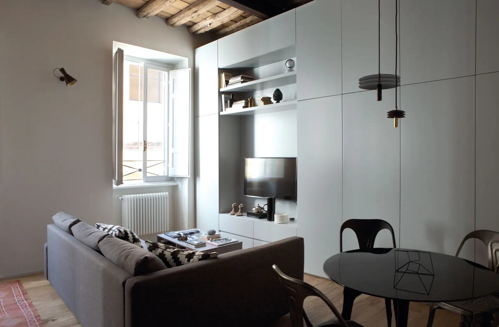 Soggiorno di Casa Monti con travi in legno a vista e boiserie chiara su misura